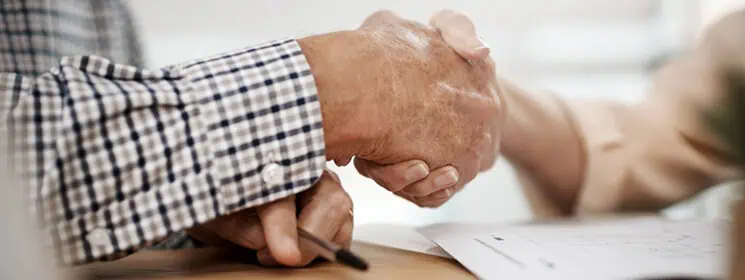 Close-up of two people shaking hands during a funeral service.