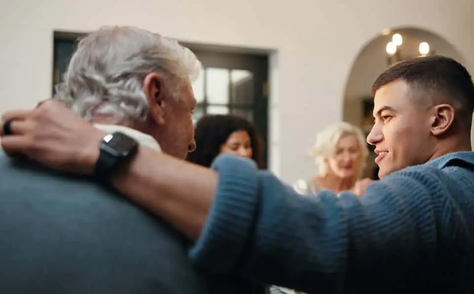 Young man comforting an elderly man at a memorial service.