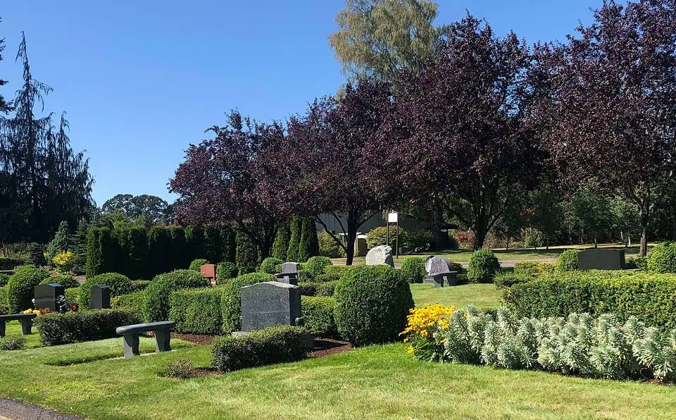View of well-maintained gravesite area with trees and benches.