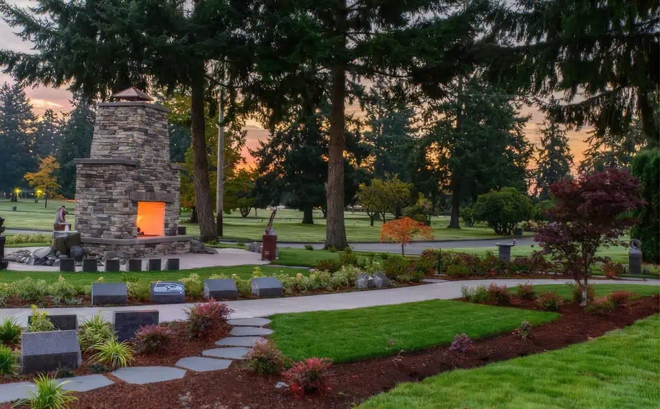 Beautiful garden with stone fireplace, trees, and colorful plants at memorial park.