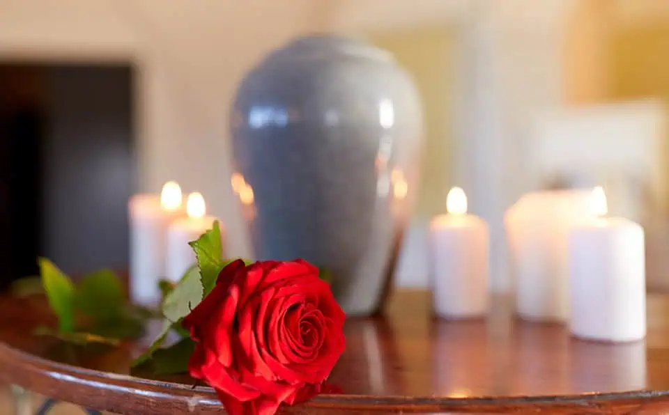 Red rose and lit candles on a wooden table at a memorial service.