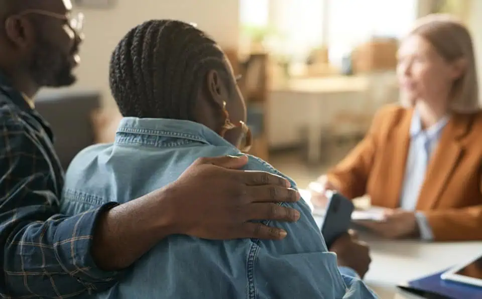 Two people offering comfort to a grieving woman during a consultation.