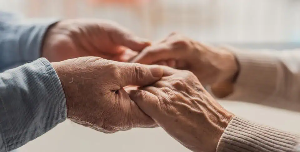 Close-up of two elderly hands holding each other gently.