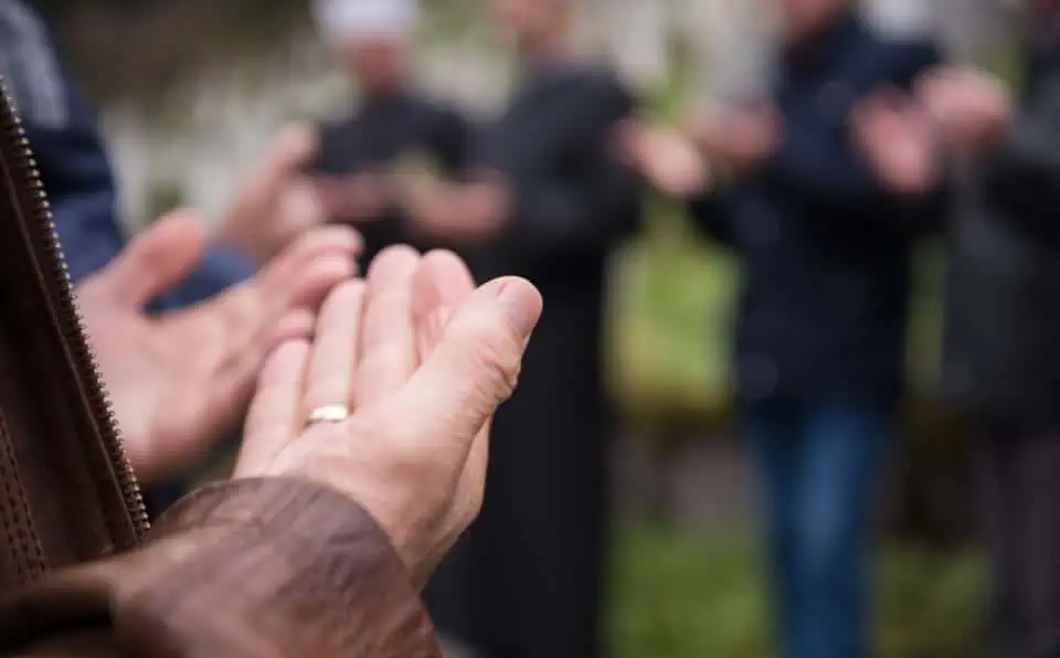 Close-up of hands in prayer during a memorial gathering.