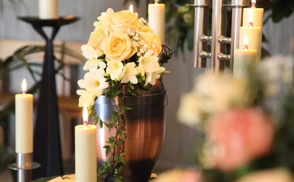 Floral arrangement with roses and candles on a memorial table.