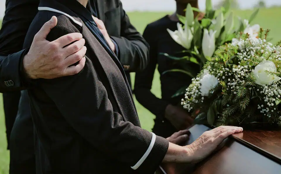 People paying respects at a funeral service outdoors.