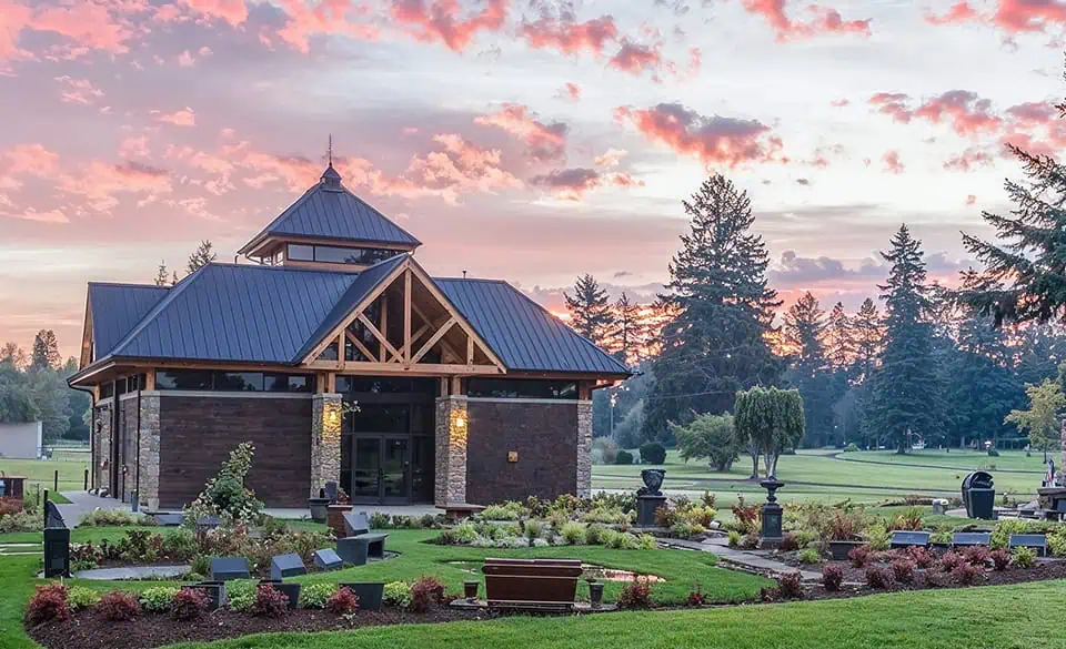 Chapel or pavilion with a metal roof and brick walls in a cemetery setting.
