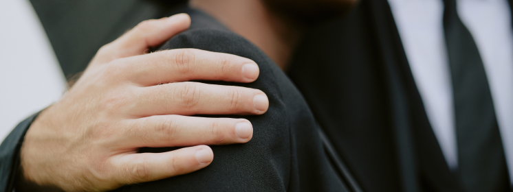 Close-up of a person's hand on another's shoulder at Memorial Park entrance.