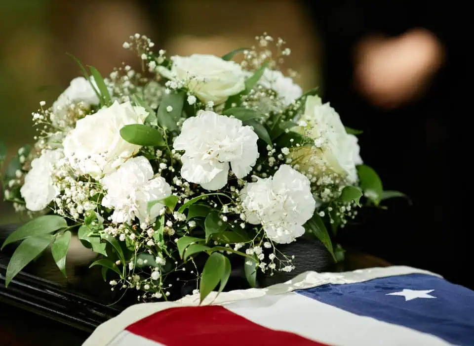 White floral arrangement with greenery on a black surface.