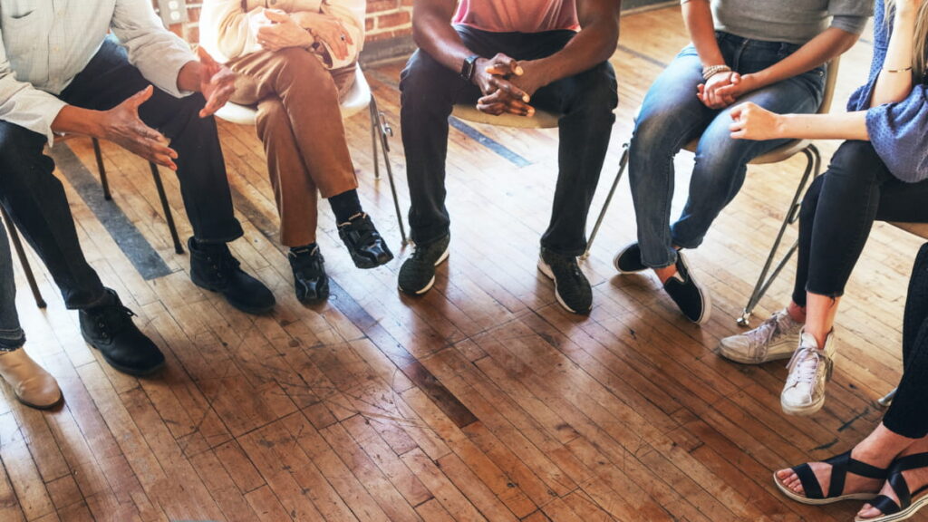 Group of diverse people sitting in a circle during a support group session.